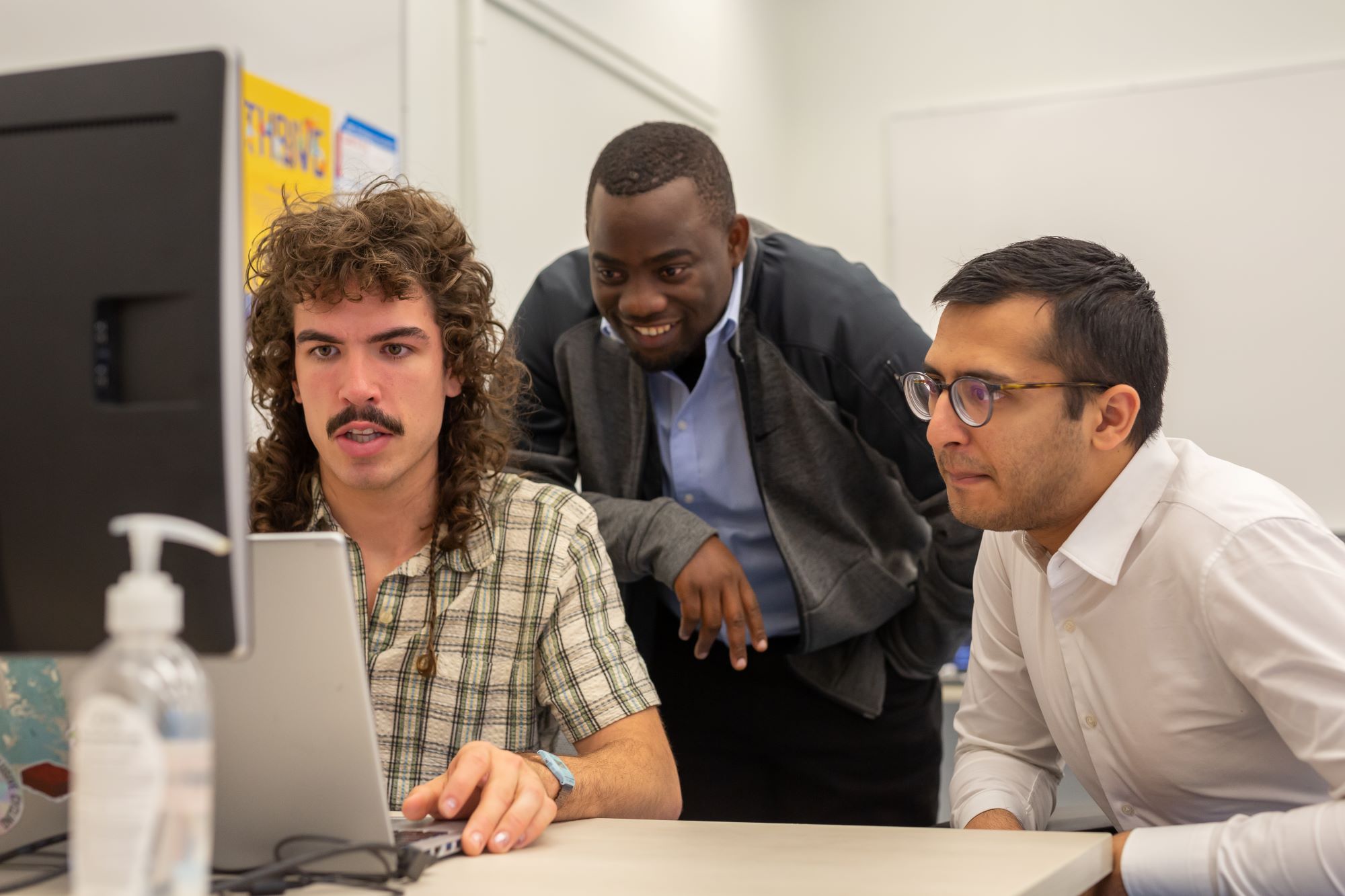 researchers looking at the computer screen while one is explaining his findings