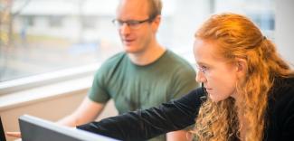 Two people looking at a desktop screen together.